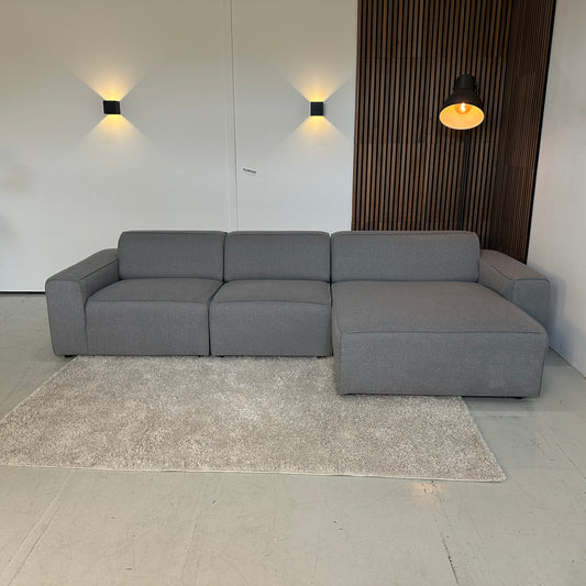 Grijze modulaire hoekbank van stof met strakke lijnen en moderne uitstraling